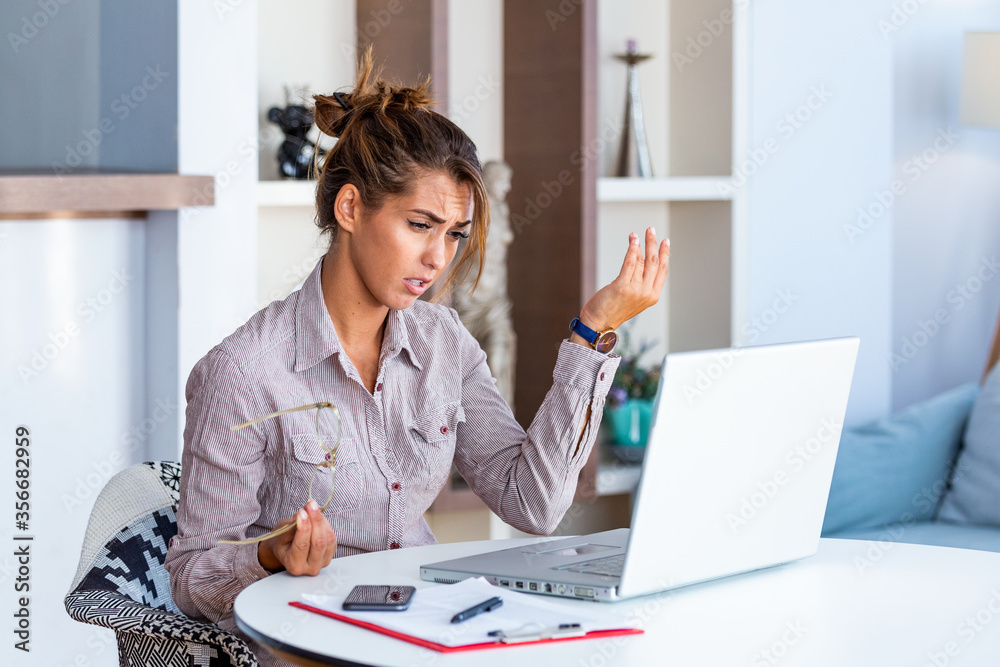 Young businesswoman misunderstanding her laptop at her desk in office. woman working with laptop at home or modern office. Serious, confused, or frustrated expression. Young businesswoman misunderstanding her laptop at her desk in office. woman working with laptop at home or modern office. Serious, confused, or frustrated expression.
