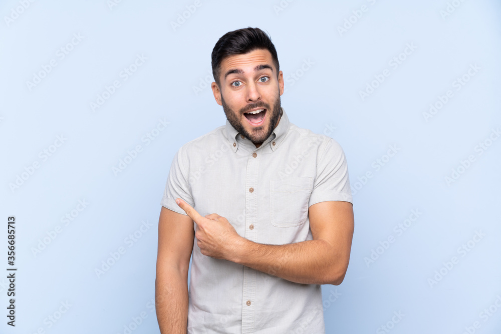 Young handsome man with beard over isolated blue background pointing finger to the side Young handsome man with beard over isolated blue background pointing finger to the side