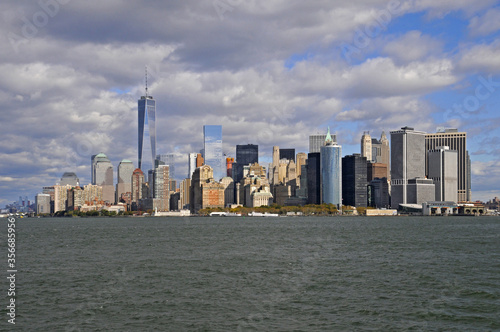 Vue panoramique sur la pointe sud de manhattan, le quartier des affaires, battery park, le world trade center et les gratte-ciel sur fond de ciel nuageux et bleu depuis le fleuve. photo