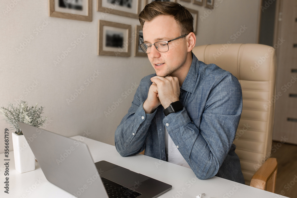 Naklejka premium Young man working online at home or study using laptop at the table. 