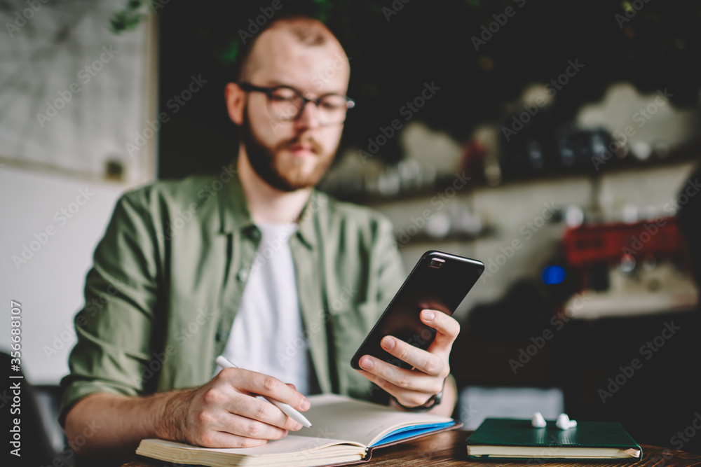 Bearded hipster guy holding mobile phone in hands and chatting Bearded hipster guy holding mobile phone in hands and chatting