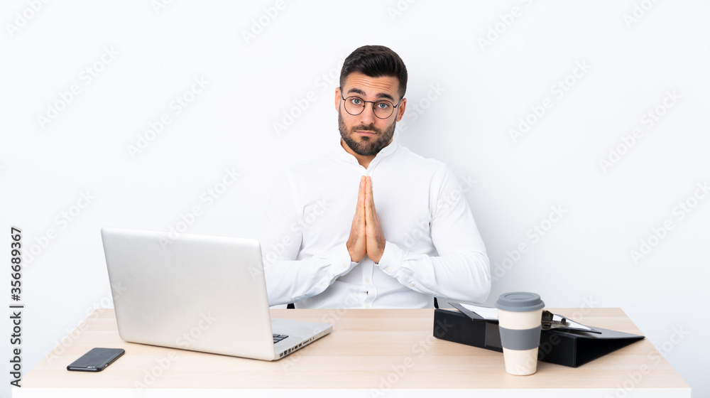 Young businessman in a workplace keeps palm together. Person asks for something Young businessman in a workplace keeps palm together. Person asks for something