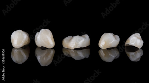 ceramic high-quality dental tabs - crowns on black glass with reflection