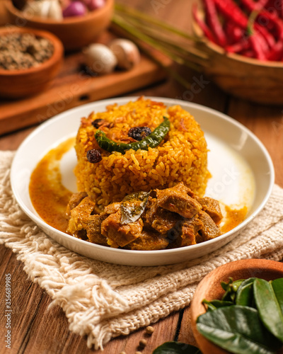 Indian Mutton Biryani Dish served on wooden table. Typical food from India, made from goat meat mixed with spices and basmati rice