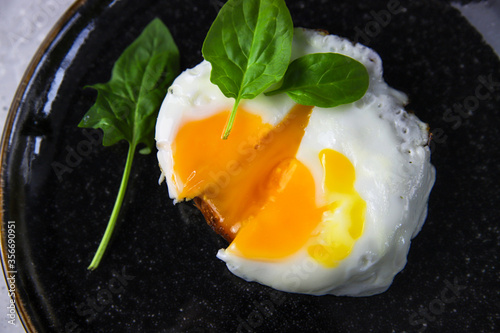 Fried egg toast with fresh baby spinach on black plate on gray concrete background. Tasty healthy breakfast. Morning food, top veiw
 photo