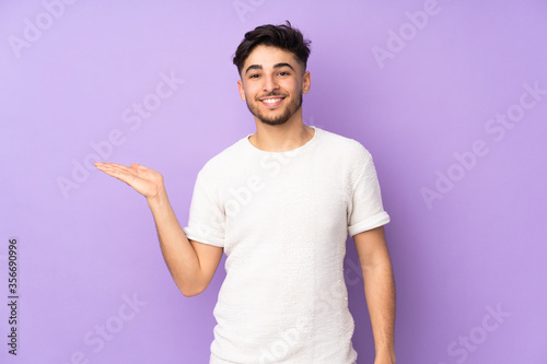 Arabian handsome man over isolated background holding copyspace imaginary on the palm to insert an ad