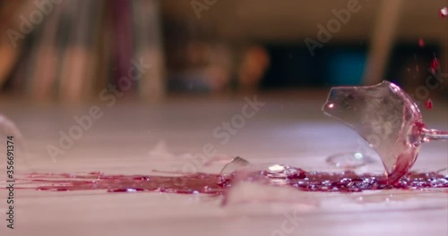 Glass of wine smashing on floor slow motion. Breaking wine glass
