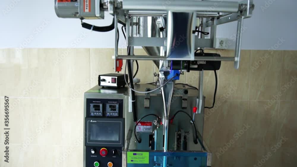 The working process of the metal technical device at the enterprise for packing in plastic sachets foodstuff, the heated mechanical metal press creates packing, a side view, a close-up The working process of the metal technical device at the enterprise for packing in plastic sachets foodstuff, the heated mechanical metal press creates packing, a side view, a close-up