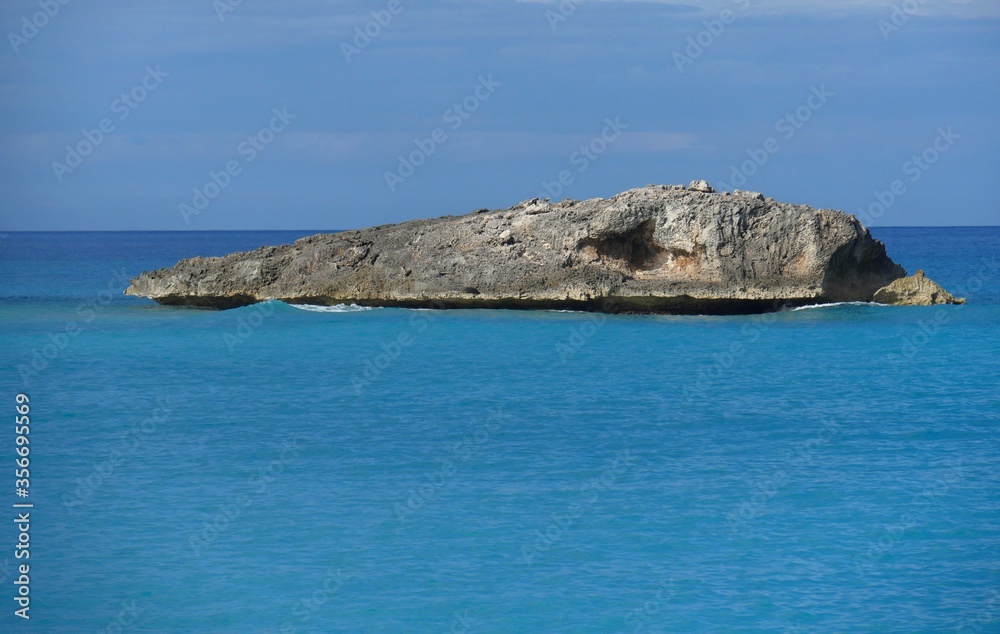 Beautiful rock island n the middle of turquoise blue waters in a tropical island