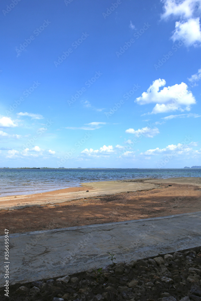 beautiful vertical panorama landscape view of an empty yellow sand beach in shadow, turquoise ocean water, light blue sky, white clouds and islands on the horizon. Island of Koh Lanta, Thailand beautiful vertical panorama landscape view of an empty yellow sand beach in shadow, turquoise ocean water, light blue sky, white clouds and islands on the horizon. Island of Koh Lanta, Thailand
