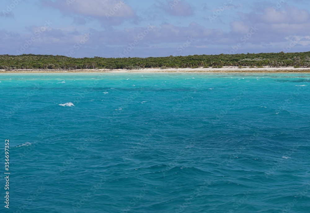 Different hues of blue waters with a beautiful island in the islands of the Exuma Cays, Bahamas.