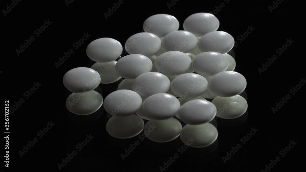 Close-up view of white medical pills rotating at black background. Pills and drugs. Pharmaceutical Industry. The medicine concept. Close-up view of white medical pills rotating at black background. Pills and drugs. Pharmaceutical Industry. The medicine concept.