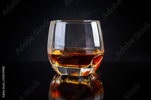 Glass of whiskey on dark background.