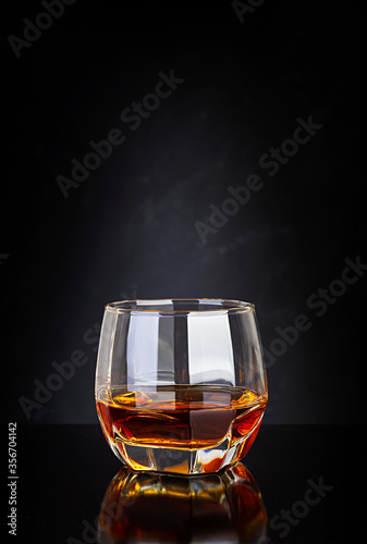 Glass of whiskey on dark background.
