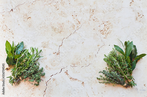 Travertine background with fresh herbs in corners and copy space