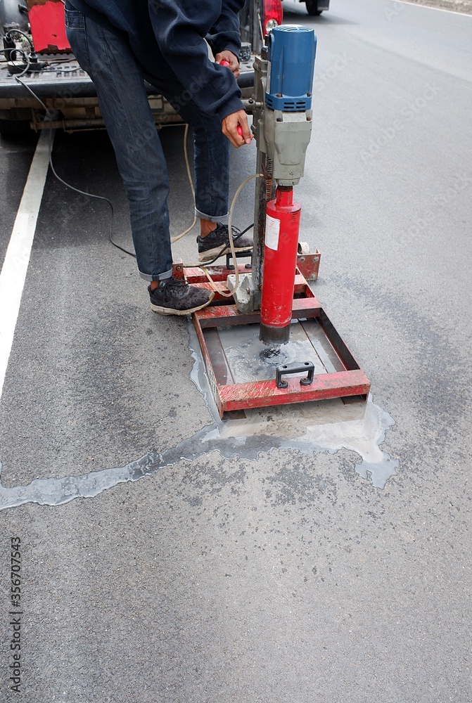 Road surface drilling machine, asphalt asphalt concrete road, workers, check the surface layer thickness, water on the floor, red machinery,copy space Road surface drilling machine, asphalt asphalt concrete road, workers, check the surface layer thickness, water on the floor, red machinery,copy space