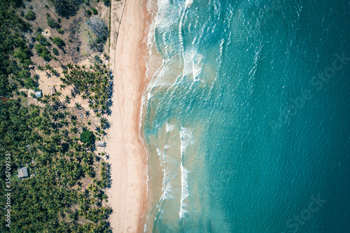 Aerial view to tropical sandy beach and blue ocean. Top view of ocean waves reaching shore on sunny day. Palawan, Philippines.