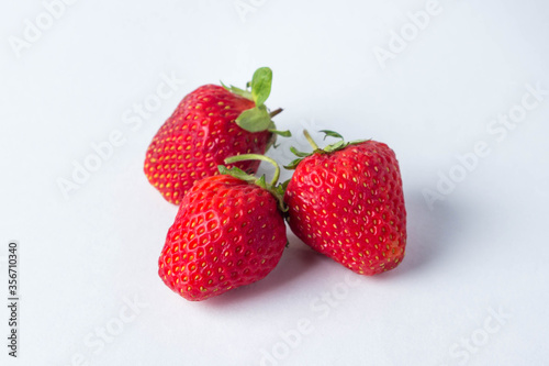 Strawberries on a white background. Three red  ripe and juicy strawberries. Strawberries lie close to each other