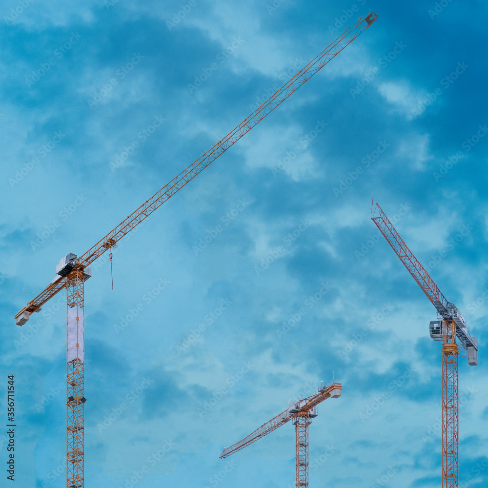 Cranes of a construction site against blue sky Cranes of a construction site against blue sky