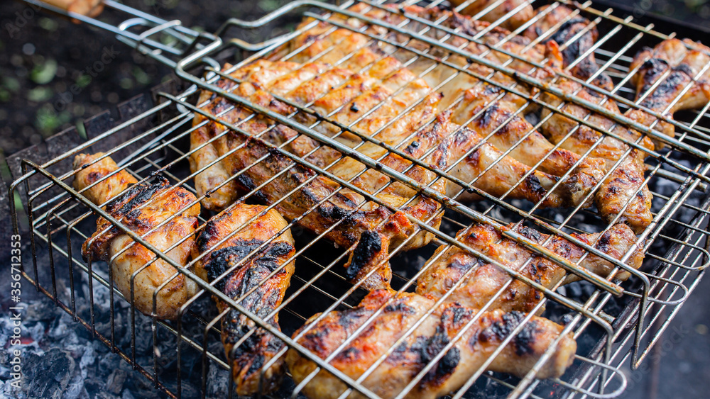 The process of frying chicken meat on the grid a barbecue in the backyard.