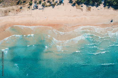 Aerial view to tropical sandy beach and blue ocean. Top view of ocean waves reaching shore on sunny day. Palawan  Philippines.