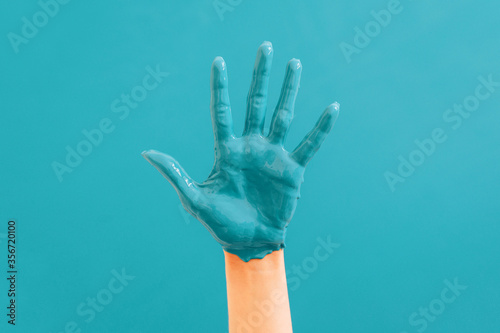 Woman's hand close-up in blue paint on a blue background. Repairs concept.