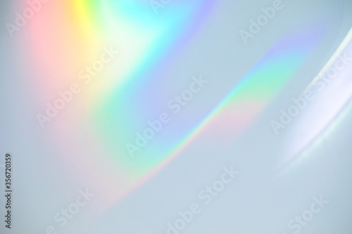 Blurred rainbow light refraction texture overlay effect for photo and mockups. Organic drop diagonal holographic flare on a white wall. Shadows for natural light effects photo