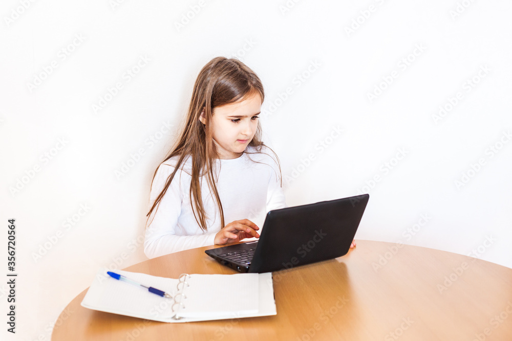 Girl, school girl doing homework at home at the table on a laptop, computer, notes, notebook, school, learning at home Girl, school girl doing homework at home at the table on a laptop, computer, notes, notebook, school, learning at home