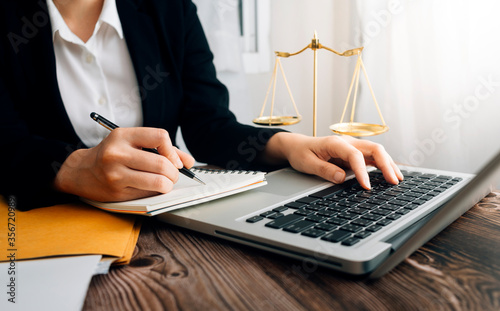 Justice and law concept.Male judge in a courtroom with the gavel, working with, computer and docking keyboard, eyeglasses, on table in morning light