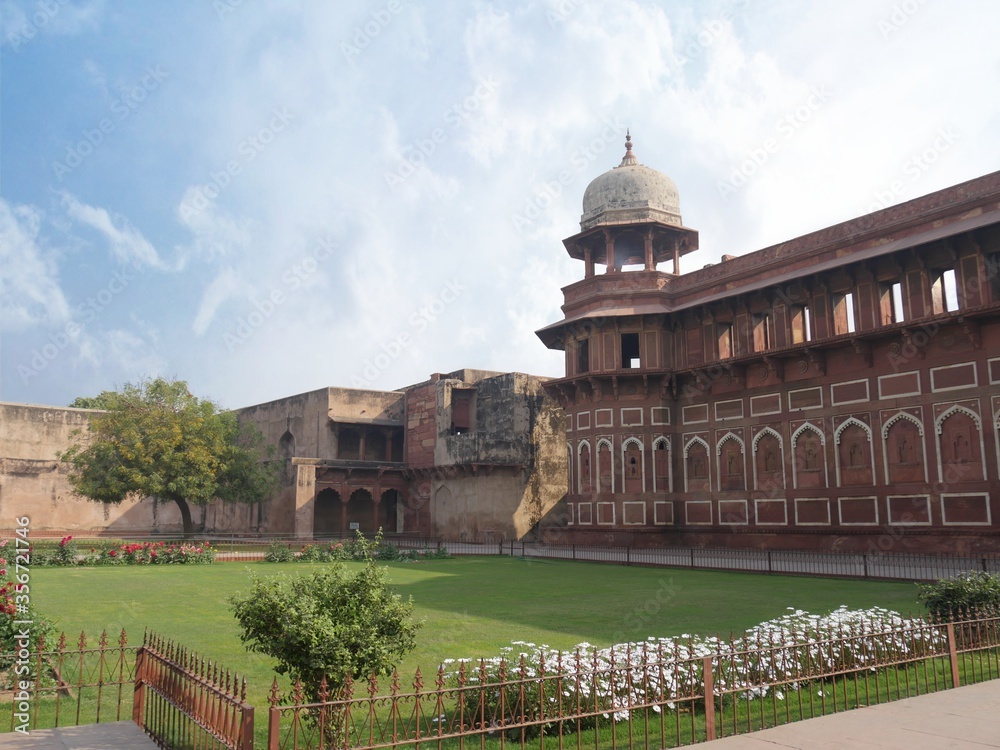 Medium wide shot of the side of Jahangiri Mahal at the Agra Fort, with white flowers blooming in the garden