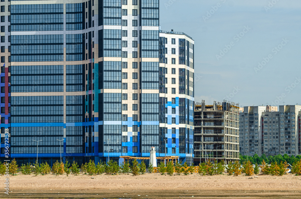 Construction of a residential complex by the sea. The progress of construction of the residential complex Morskaya embankment. Houses in the sand by the water. Russia, St. Petersburg, June 9, 2020