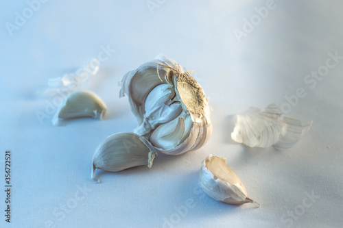 Image of garlic in a half bulb separate into pieces with a white background.