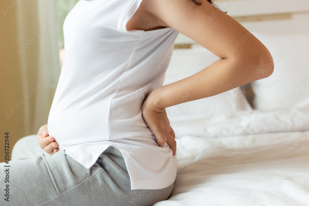 Foto de Pregnant woman touching tummy and suffering from back ache
