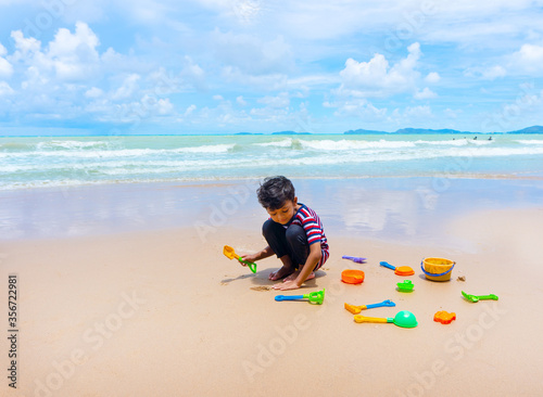 Little asian boy play with sand on the beach.