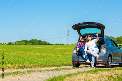 Wallpaper Mural Mother and daughter share a day outdoors. They are sitting in the car trunk compartment and they are taking a selfie. Torontodigital.ca