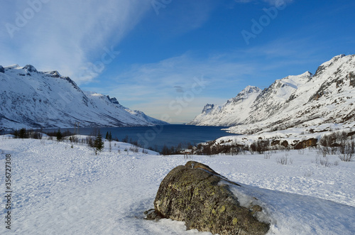 majestic tall snowy mountain with vibrant blue sky and fjord © Arcticphotoworks
