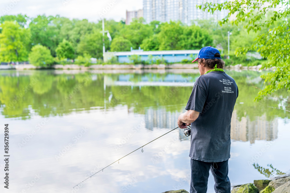 Manhattan, New York - May 30, 2020: Fisherman Casts His Line off the Inwood Hill Park Shores. Manhattan, New York - May 30, 2020: Fisherman Casts His Line off the Inwood Hill Park Shores.