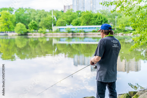 Manhattan, New York - May 30, 2020: Fisherman Casts His Line off the Inwood Hill Park Shores.