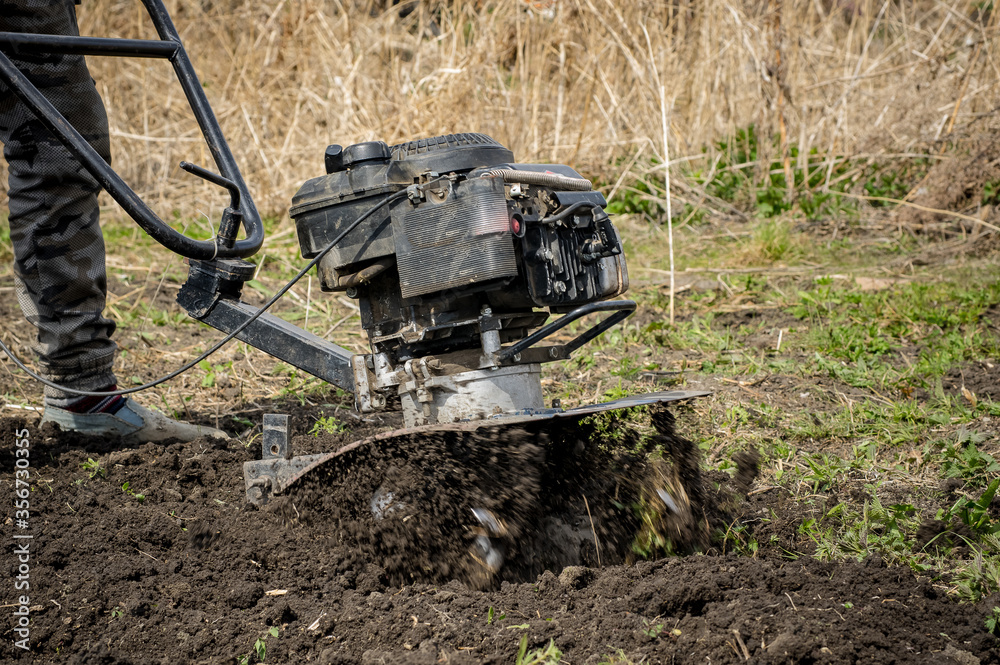 a man cultivates the land with a motorcycle cultivator a man cultivates the land with a motorcycle cultivator