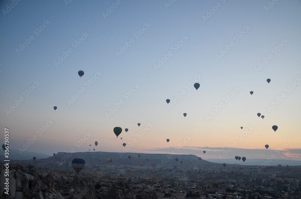 Hot air balloons at sunrise flying in the sky along valleys at Cappadocia of Goreme, Turkey Hot air balloons at sunrise flying in the sky along valleys at Cappadocia of Goreme, Turkey