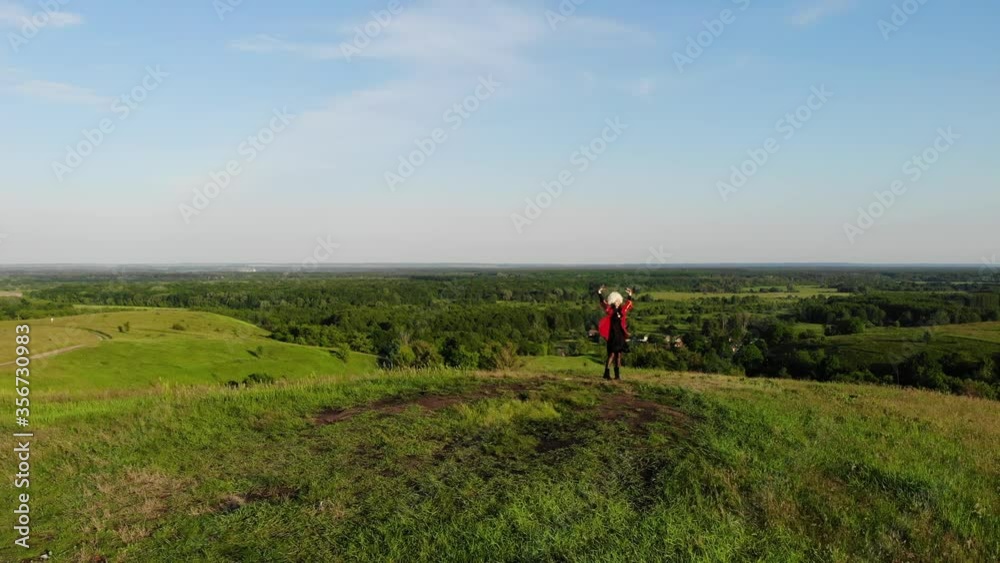 Georgian girl dances national dance from drone in white papakha and red national dress. Dance named: rachuli, acharuli, osuri, shalaxo, mtiuluri. on the green hills. Georgian culture lifestyle. Georgian girl dances national dance from drone in white papakha and red national dress. Dance named: rachuli, acharuli, osuri, shalaxo, mtiuluri. on the green hills. Georgian culture lifestyle.