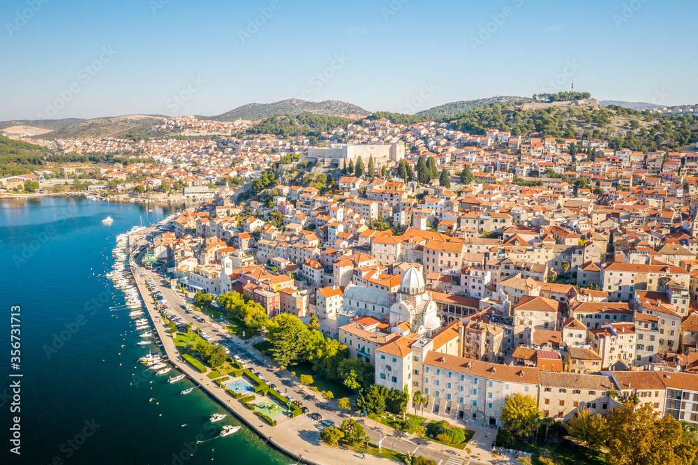 Aerial view of houses surrounded by turquoise water on sunny day in Sibenik, Croatia
