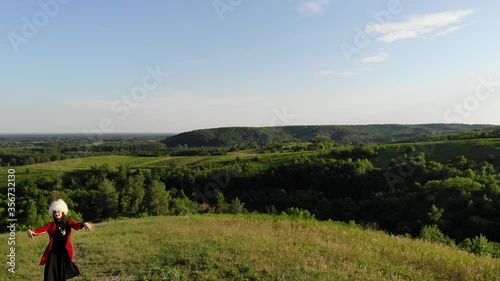Wallpaper Mural Georgian girl dances national dance from drone in white papakha and red national dress. Dance named: rachuli, acharuli, osuri, shalaxo, mtiuluri. on the green hills. Georgian culture lifestyle. Torontodigital.ca