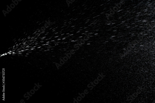 Aerosol splash background. Liquid water spray mist from perfume bottle isolated on black. photo