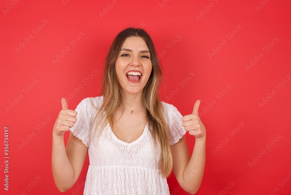 Closeup of young optimistic female isolated on grey background showing thumbs up with positive emotions of content and happiness. Copyspace, concept of satisfaction with quality and recommendation. Closeup of young optimistic female isolated on grey background showing thumbs up with positive emotions of content and happiness. Copyspace, concept of satisfaction with quality and recommendation.