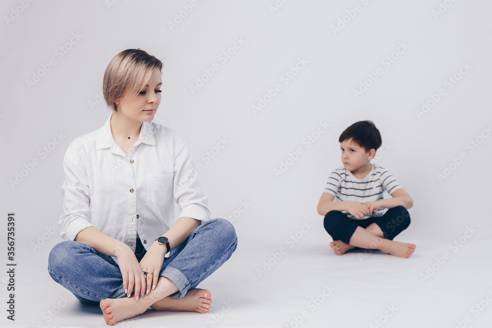 White background. Mom sits in the lotus position in front, her son sits behind as well. White background. Mom sits in the lotus position in front, her son sits behind as well.