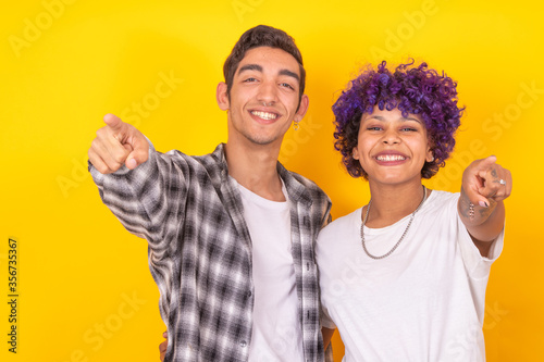 young couple of man and woman pointing isolated on color background