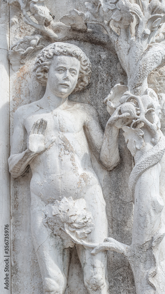 Ancient aged sculpture of beautiful Eva with apple and Adam from Bible story of Creation at Doge Palace in Venice, Italy, closeup, details