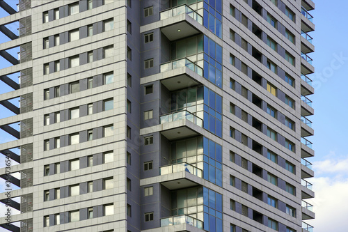 Glass blue square Windows of facade modern city business building skyscraper. Balconies in the building. Modern apartment buildings in new neighborhood. Abstract architecture. Texture.