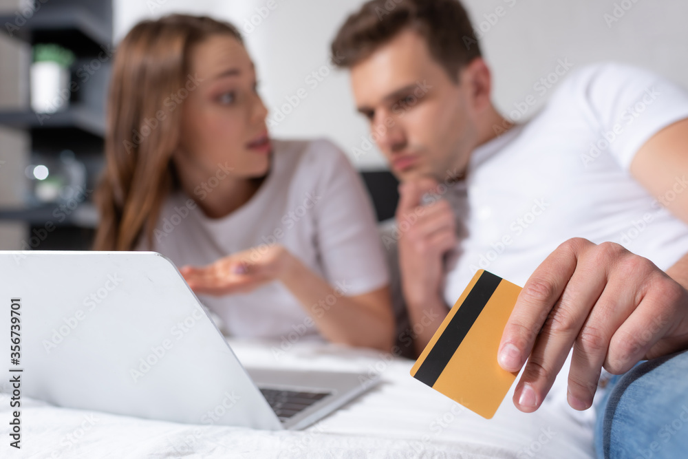 selective focus of pensive man holding credit card near girl and laptop selective focus of pensive man holding credit card near girl and laptop